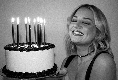  female laghing while holding cake with candles on top