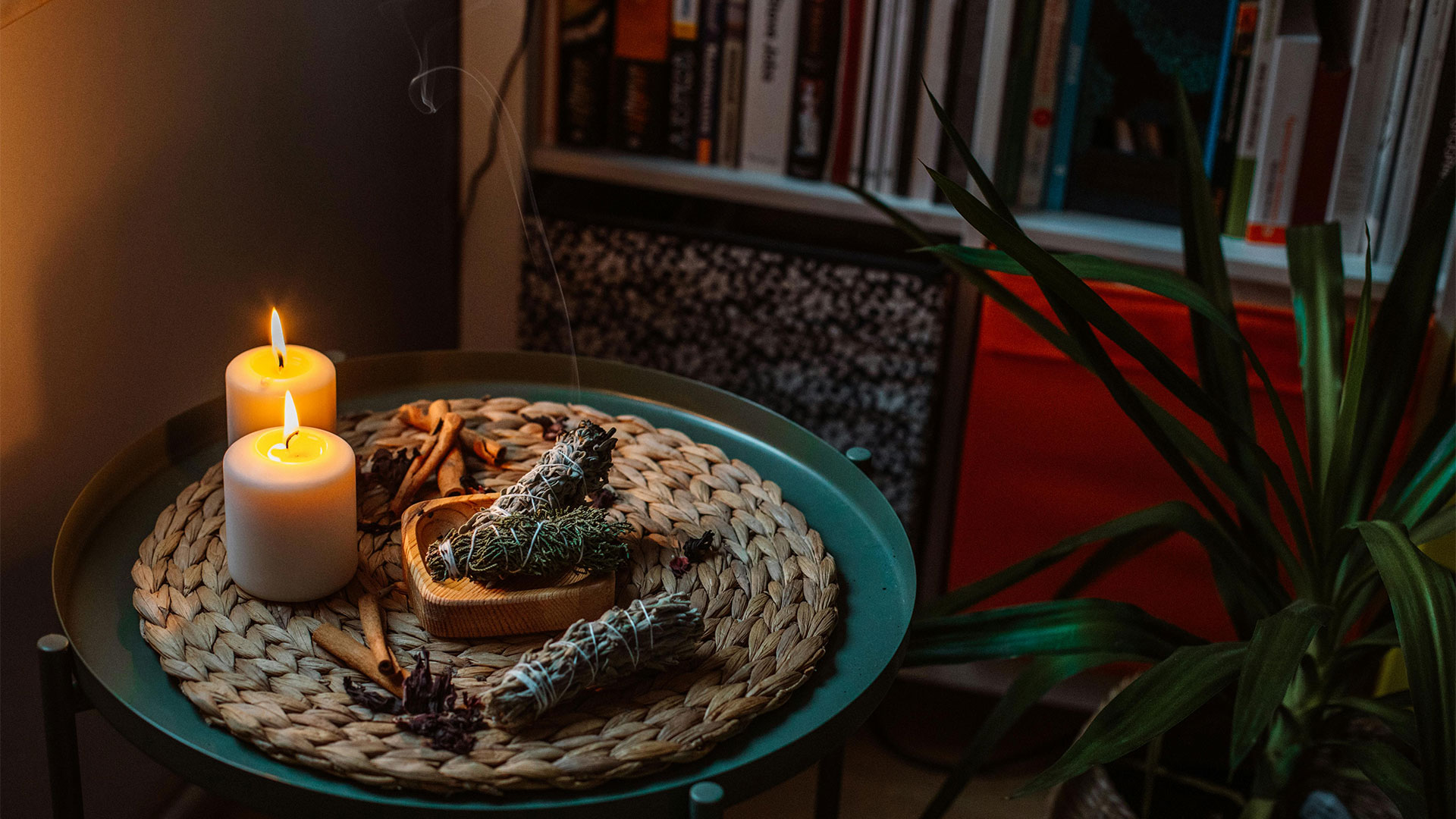  candles in a dark libraby with herbal plants around it 