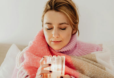  girl in bed smelling or admiring the candle